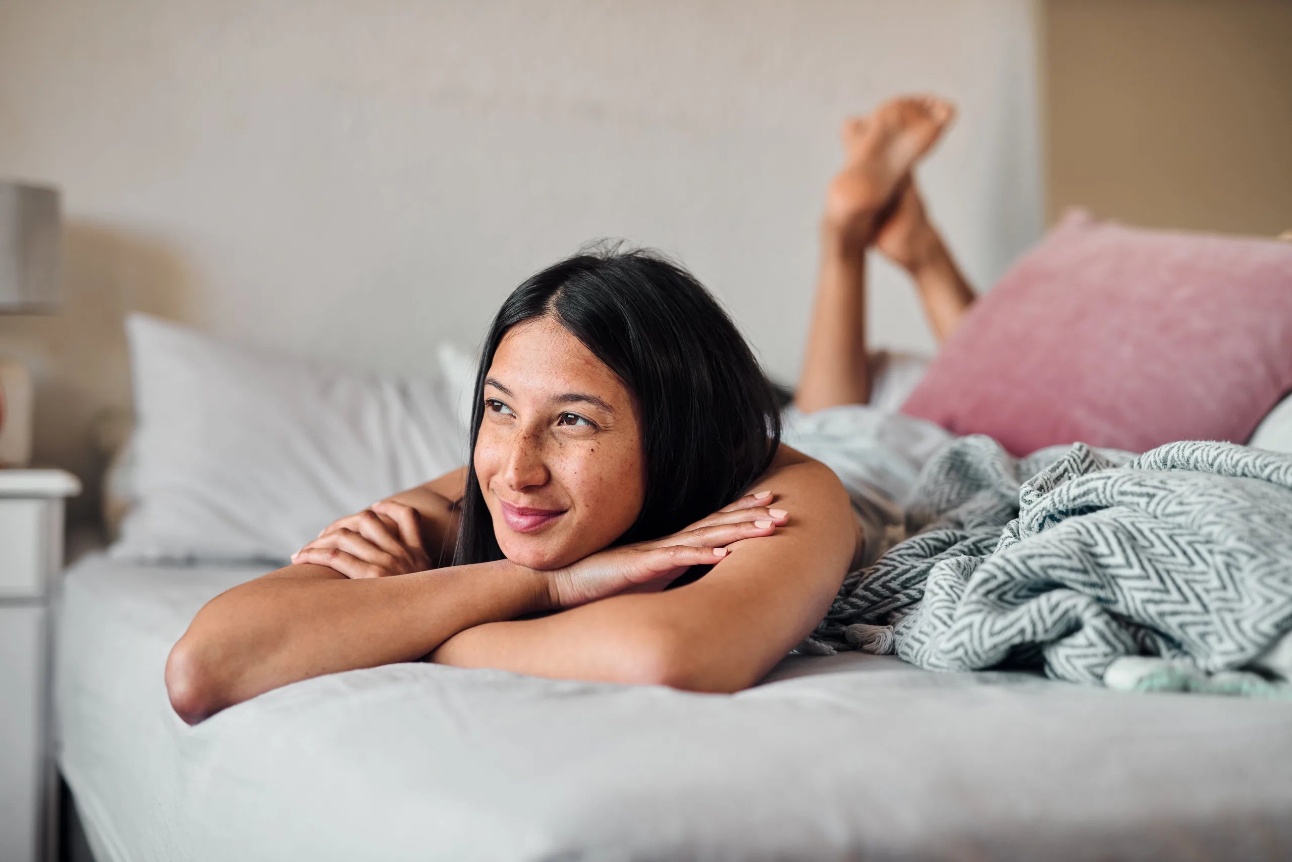 Eine Frau liegt auf einem Bett und blickt zuversichtlich in die Zukunft